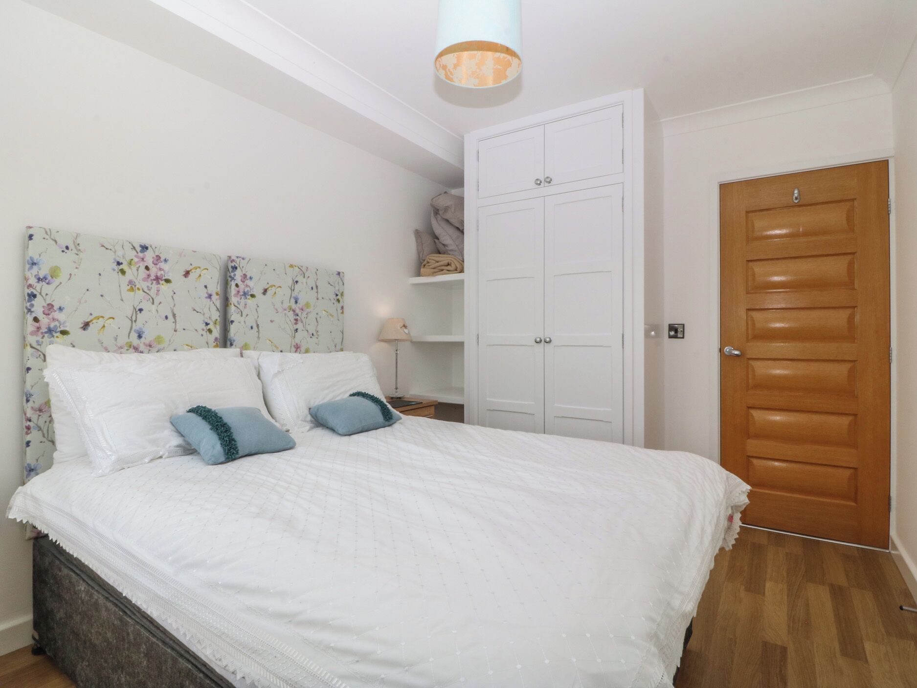 Un dormitorio con cama, armario, mesita de noche y puerta.