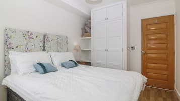 Un dormitorio con cama, armario, mesita de noche y puerta.
