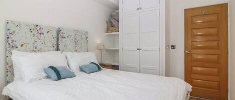 Une chambre à coucher avec un lit, une armoire, une table de chevet et une porte.
