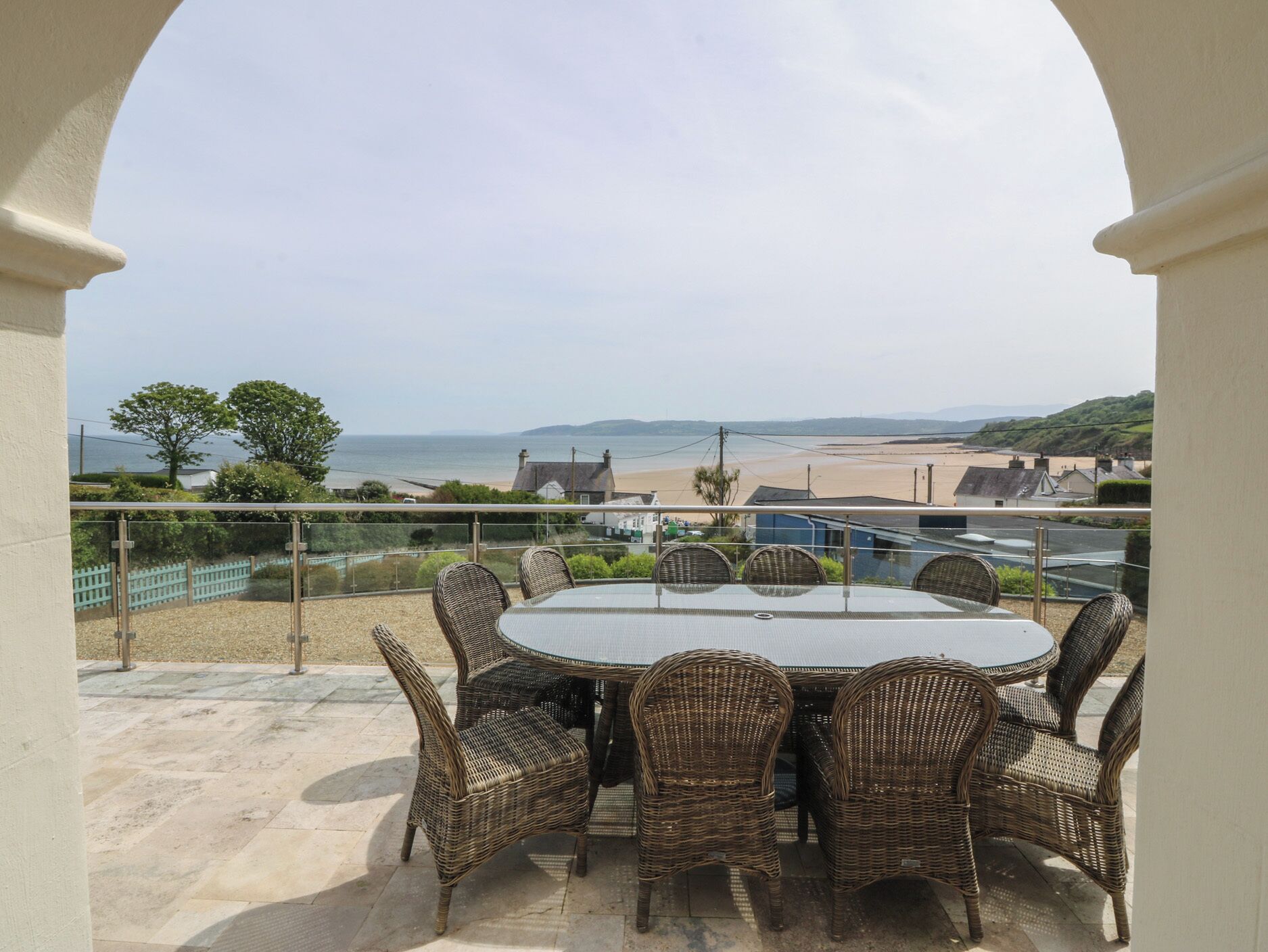 A patio with wicker furniture and a view of the beach.