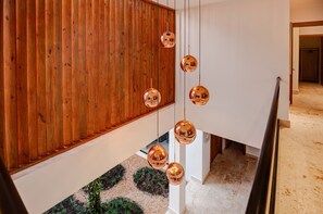 Ein modernes Interieur mit Holzvertäfelung, einer weißen Treppe und kugelförmigen Pendelleuchten.