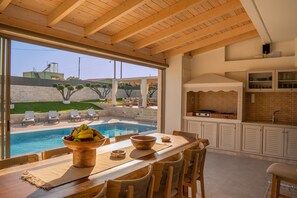 Eine Außenküche mit Pool, Essbereich und Blick auf die umliegende Landschaft.
