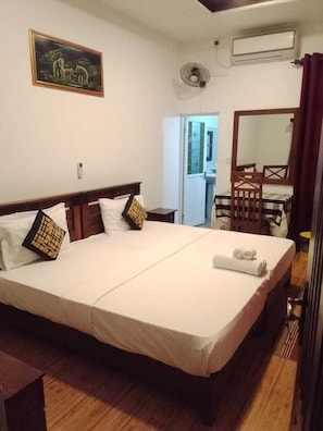 Una camera d'albergo con un letto grande, un comodino, una sedia, una scrivania, uno specchio e un quadro appeso al muro.