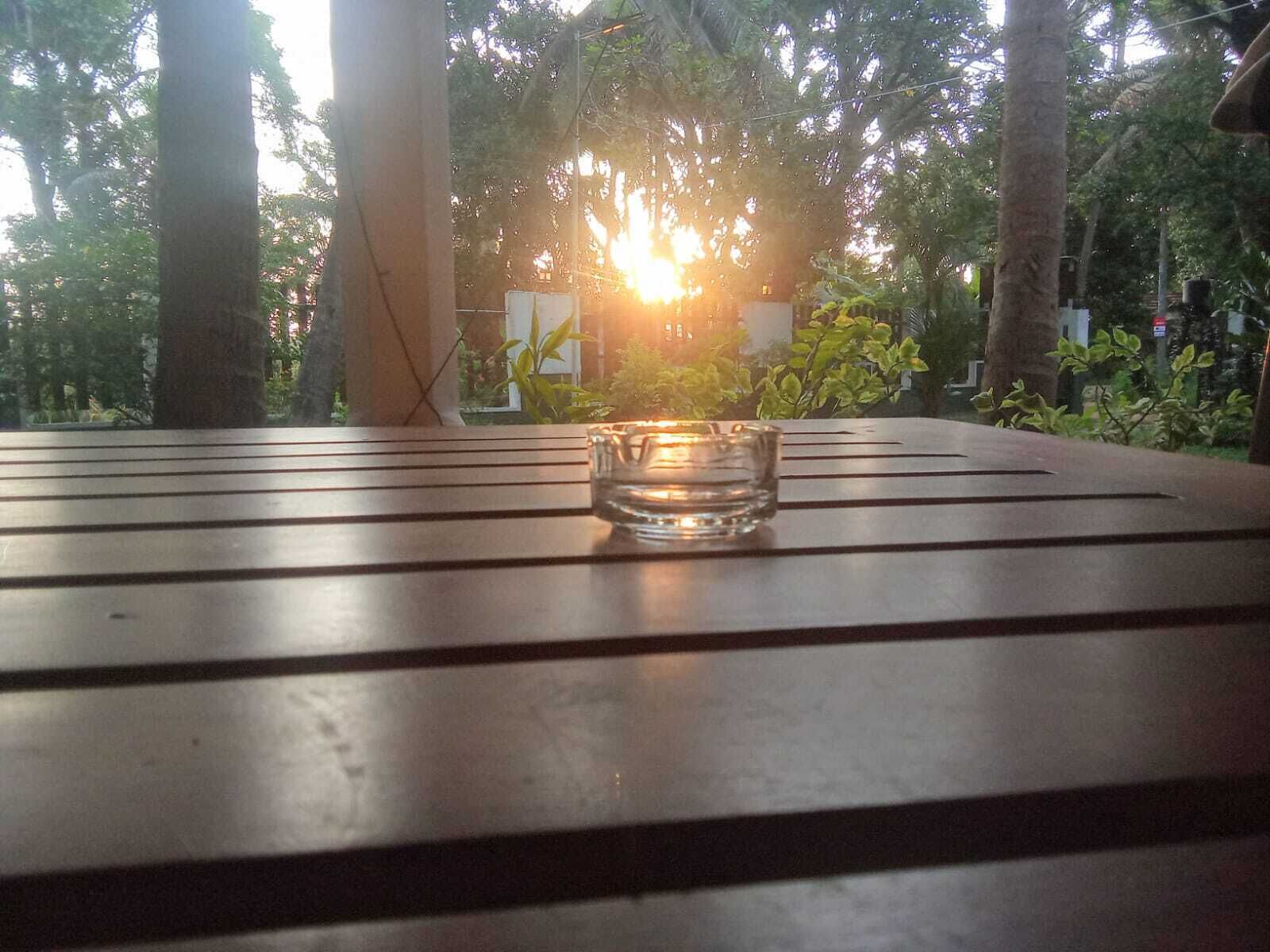 Una mesa con una vela en un candelabro, rodeada de árboles y un edificio al fondo.