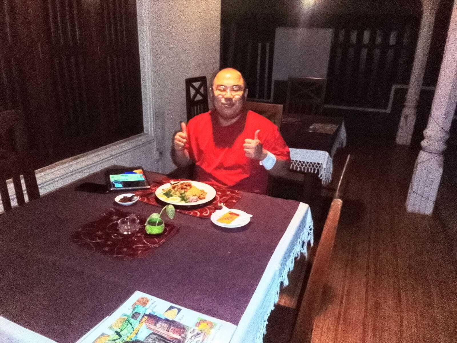 A person seated at a table with a smartphone, a plate of food, and a drink.