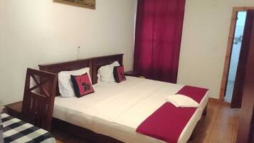 A standard hotel room with a bed, a bedside table, a chair, and a window with curtains.