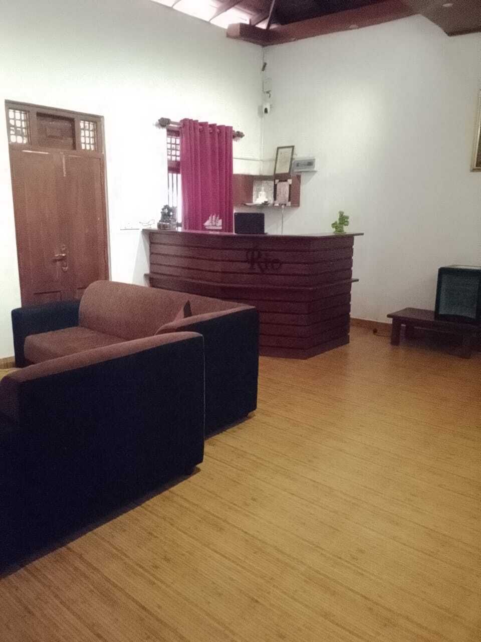 Um quarto com piso de madeira, um sofá, uma mesinha, um armário de madeira e uma porta.