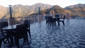 Une terrasse extérieure avec des tables et des chaises, un sol à motifs et une vue sur les montagnes.