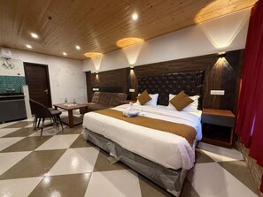 Una camera d'albergo con pavimento a scacchi, un letto con testiera, un tavolino con sedie e un lampadario a parete.