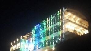 Un immeuble à étages, doté d’un balcon et illuminé par des guirlandes lumineuses verticales.