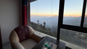 Une pièce avec une grande fenêtre, un fauteuil en cuir et une table sur laquelle se trouvent deux bouteilles.