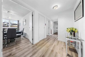 Um interior moderno com área de jantar, corredor e uma pequena mesa com flores.