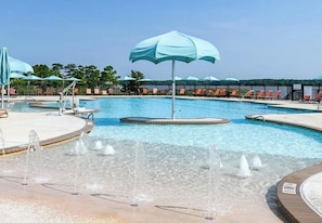 A swimming pool with multiple lanes, lounge chairs, and umbrellas.