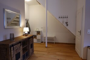 Ein Flur mit Holzboden, einem Spiegel, einer Lampe, einer Bank, einem Garderobenschrank und einer Treppe.