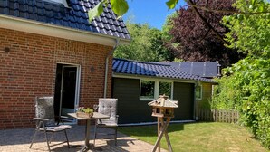 Una casa de ladrillo con un patio, una pequeña terraza y un jardín.