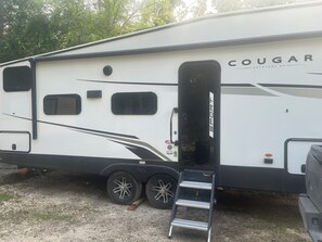 Una caravana lleugera Cougar Keystone amb una porta lateral, finestres i una escala.