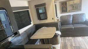 A compact living space with a kitchenette, a sofa, and a dining area. - 1 bedroom and 3 bunk bed for rent in GIMLI sandy hook (Sandy Hook)