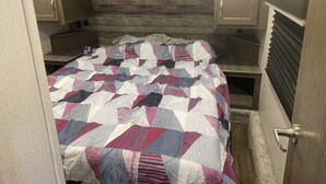 A compact bedroom with a bed, wooden headboard, and built-in cabinets. - 1 bedroom and 3 bunk bed for rent in GIMLI sandy hook (Sandy Hook)