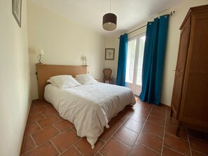 Ein Schlafzimmer mit Bett, Nachttisch, Lampe, Stuhl und Kleiderschrank.