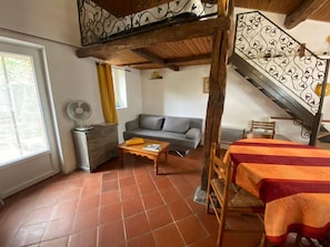 Ein Wohnzimmer mit einer Couch, einem Holztisch, einem Ventilator und einer Treppe mit einer Zierleiste.