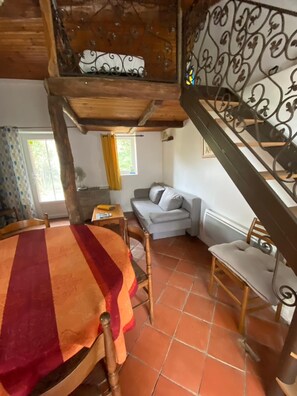 Una habitación rústica con techo de madera, una mesa de comedor con mantel a rayas, un sofá y una silla.