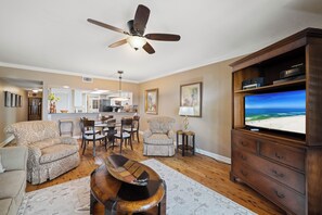Ein Wohnzimmer mit Deckenventilator, Fernseher und Holzschrank.