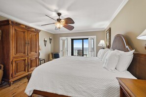 Ein Schlafzimmer mit einem großen Bett, einem Deckenventilator, einem Holzschrank und Blick ins Freie.