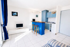 Eine moderne Küche mit einer blauen Kochinsel, weißen Schränken und einem Flachbildfernseher.