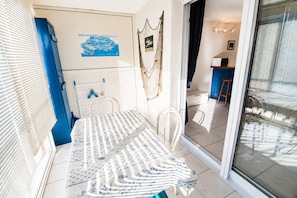 Ein Schlafzimmer mit einem Bett, einem Fenster mit Jalousien, einem Wandbild und einer Tür zu einem anderen Raum.