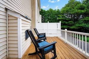 A wooden deck with two rocking chairs, a white fence, and a view of trees. - Walking Distance to night life in Huntersville (Huntersville)