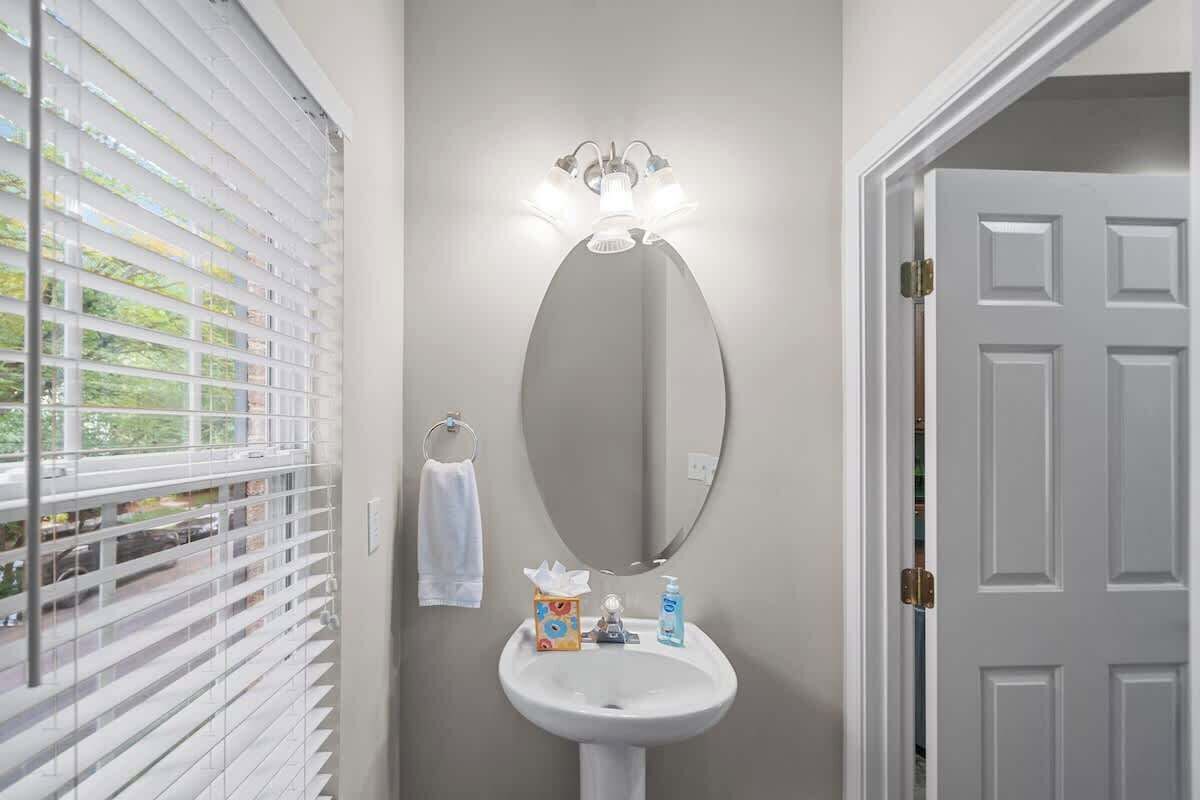A bathroom with a white sink, a mirror, and a towel rack.