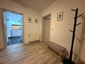 Ein Flur mit einer Bank, einem Garderobenhaken und gerahmten Bildern an der Wand.