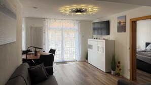 A modern living room with a sofa, a dining table, and a TV mounted on the wall. - Old town view (Stockach)