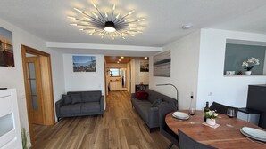 A modern living room with a dining area, wooden flooring, and a unique ceiling light fixture. - Old town view (Stockach)