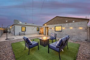A patio with a fire pit, outdoor seating, and a stone wall.