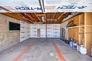 An unfinished room with insulation panels, wooden beams, and construction materials.