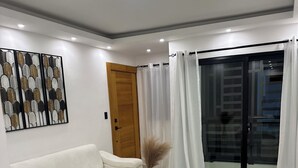 Ein modernes Wohnzimmer mit einem weißen Sofa, einem schwarzen Couchtisch und einer dekorativen Vase.
