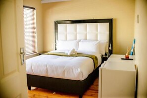 A hotel room with a bed, a small desk, and a window with blinds. - Room-makay's Guests House (Kimberley)