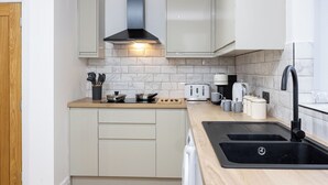 A compact kitchen with a stove, toaster, sink, and cabinets. - Entire Home Next to Trafford Centre (Stretford)