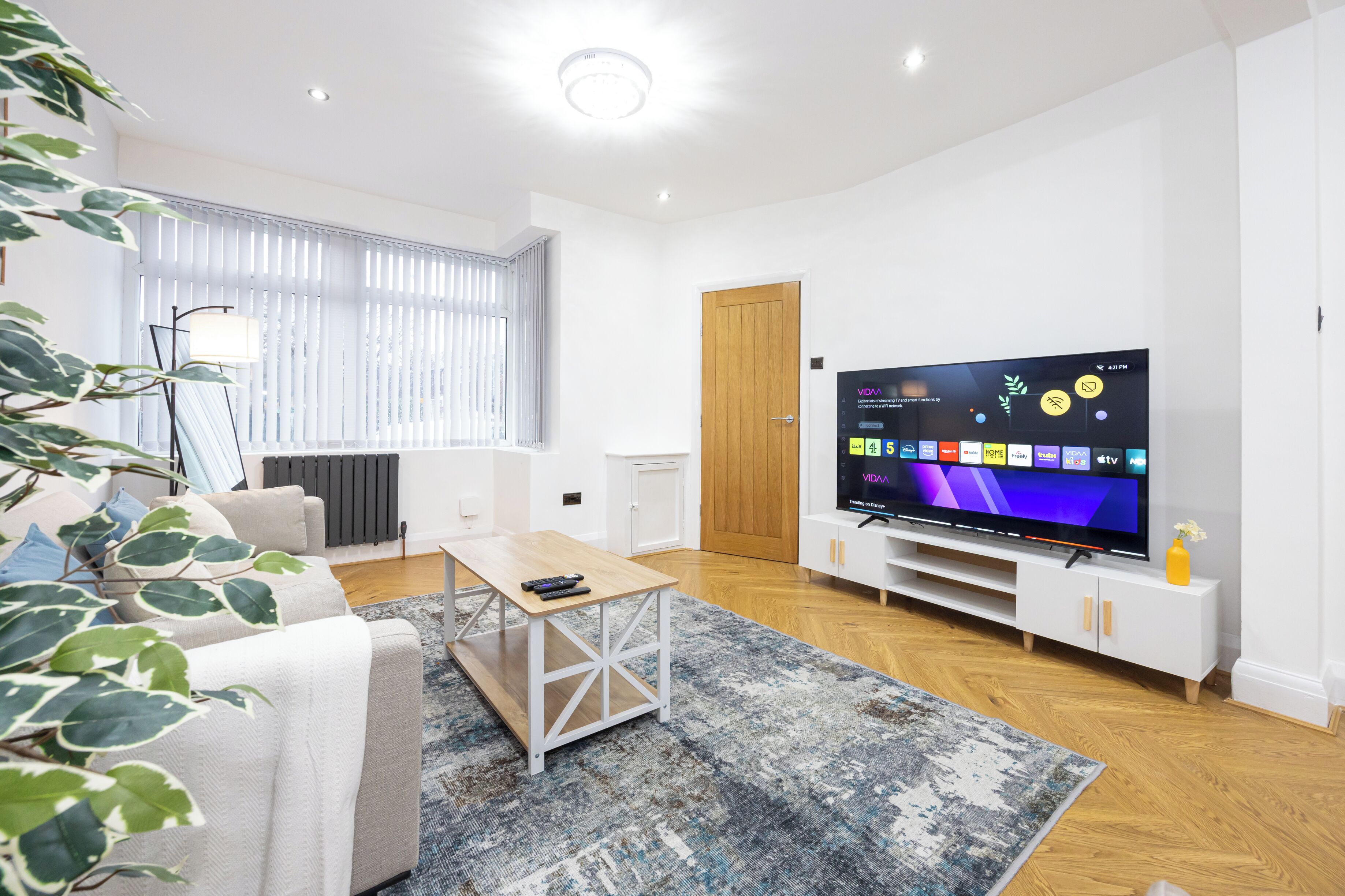 A modern living room with a TV, sofa, coffee table, and a plant.