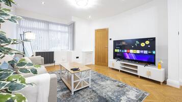 A modern living room with a TV, sofa, coffee table, and a plant.