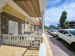 A residential building with a covered porch, a brick facade, and a parking area with cars. - G6 - ARHONTISA Studios by SDR (Paralia)