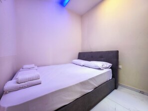 A single bed with a grey headboard, white linens, and neatly folded towels. - G6 - ARHONTISA Studios by SDR (Paralia)