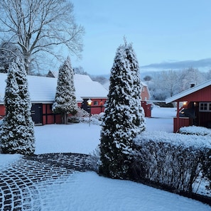 A snow-covered landscape with a red building, snow-laden trees, and a clear sky.