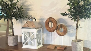 Une console en bois agrémentée de deux plantes en pot, d’une lanterne blanche et d’objets décoratifs.