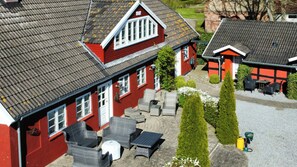 A red building with a tiled roof, outdoor seating, and a small garden area. - Historic farmhouse from 1802 near Øster Hurup (Hadsund)