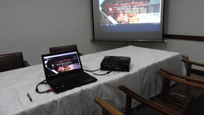A conference room with a laptop, projector, and presentation screen displaying a website. - Hotel Angasmayo (Ipiales)