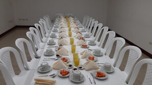 A long dining table with white chairs, arranged for a meal. - Hotel Angasmayo (Ipiales)