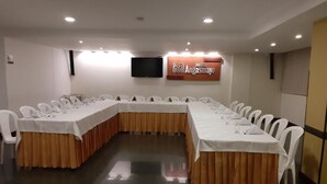 A conference room with a long table, white chairs, and a TV screen. - Hotel Angasmayo (Ipiales)