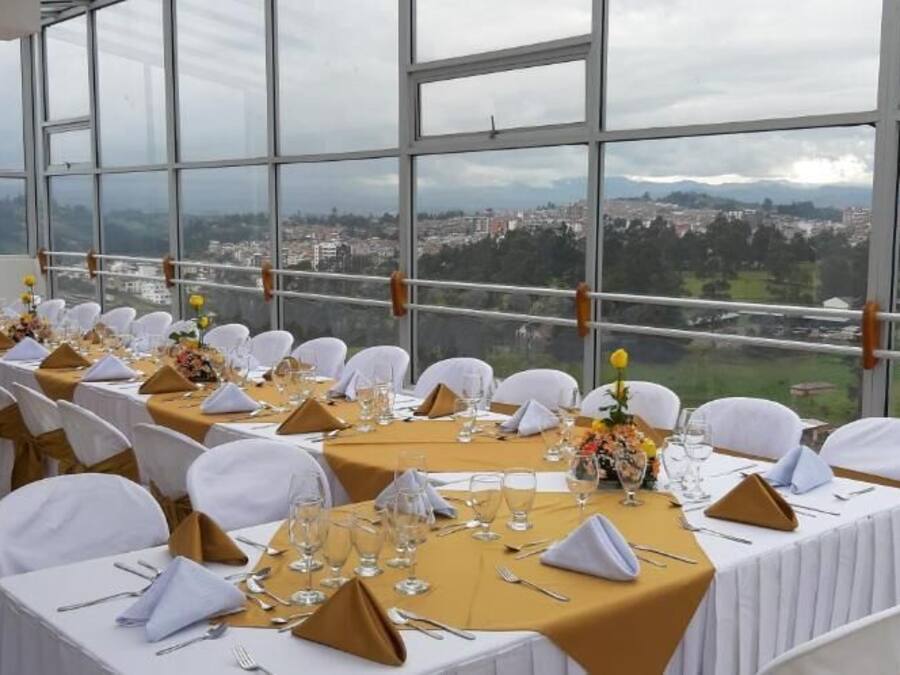A banquet hall with tables set for a formal event, large windows offering a city view.